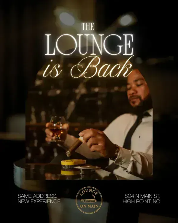 A man in a shirt and tie with a drink and cigar in a dark lounge