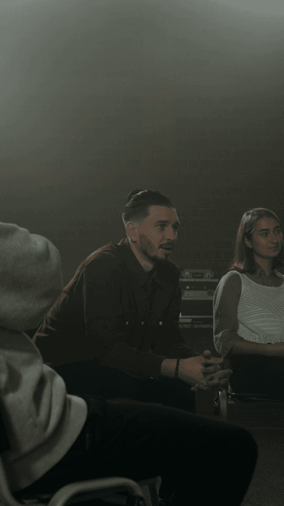 Two people in conversation with a client in a dimly lit studio